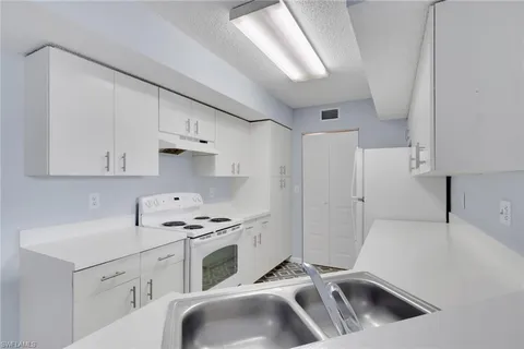 a kitchen with granite countertop a sink a stove and refrigerator