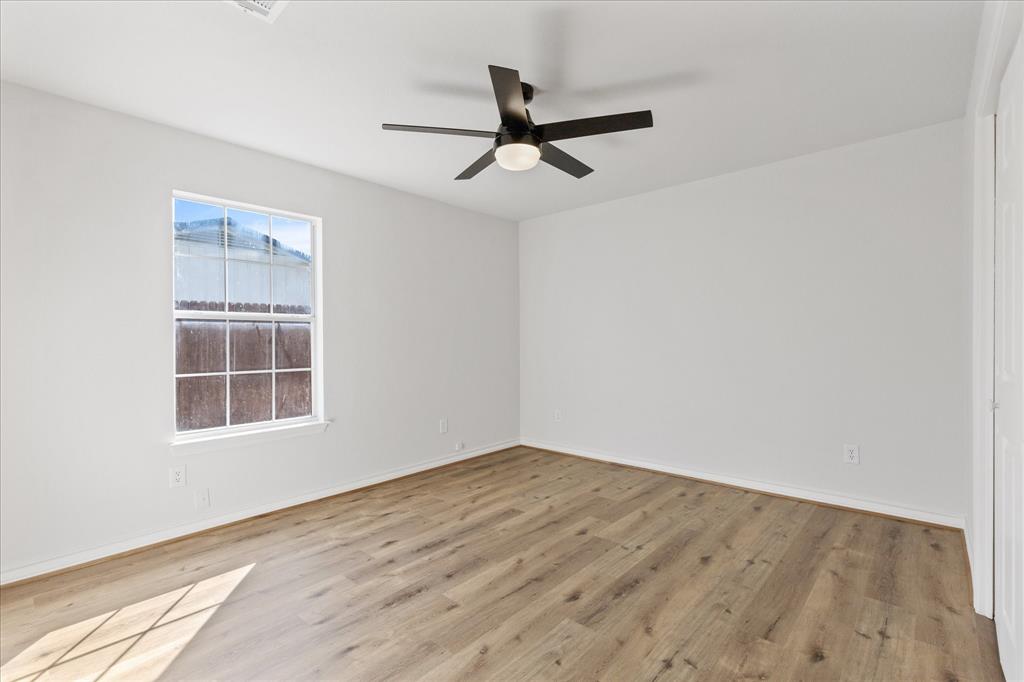 4309 Davis Road Granbury, TX 76049 - Photo 17 of 40 an empty room with wooden floor ceiling fan and windows