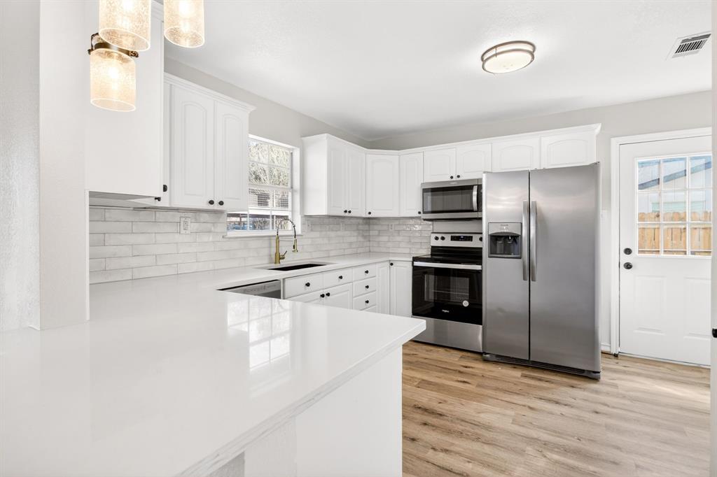 4309 Davis Road Granbury, TX 76049 - Photo 7 of 40 a kitchen with granite countertop a refrigerator and a stove top oven