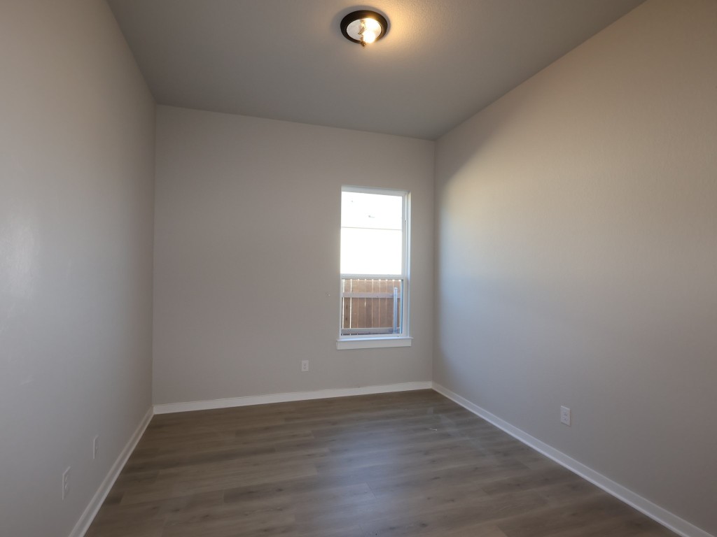 374 Bishop Wood Road Dripping Springs, TX 78620 - Photo 17 of 18 a view of an empty room with wooden floor and a window