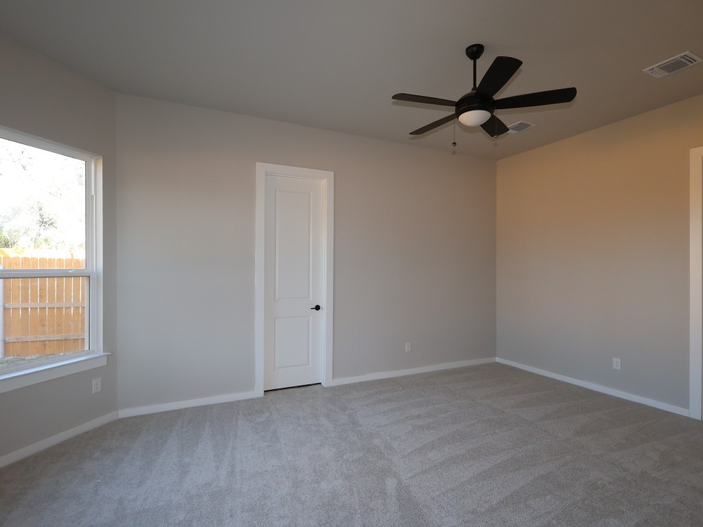 374 Bishop Wood Road Dripping Springs, TX 78620 - Photo 7 of 18 an empty room with a window and a fan