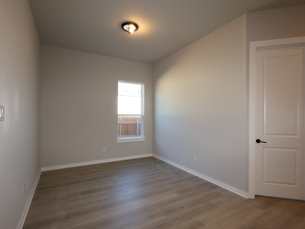 374 Bishop Wood Road Dripping Springs, TX 78620 - Photo 9 of 18 an empty room with wooden floor and windows