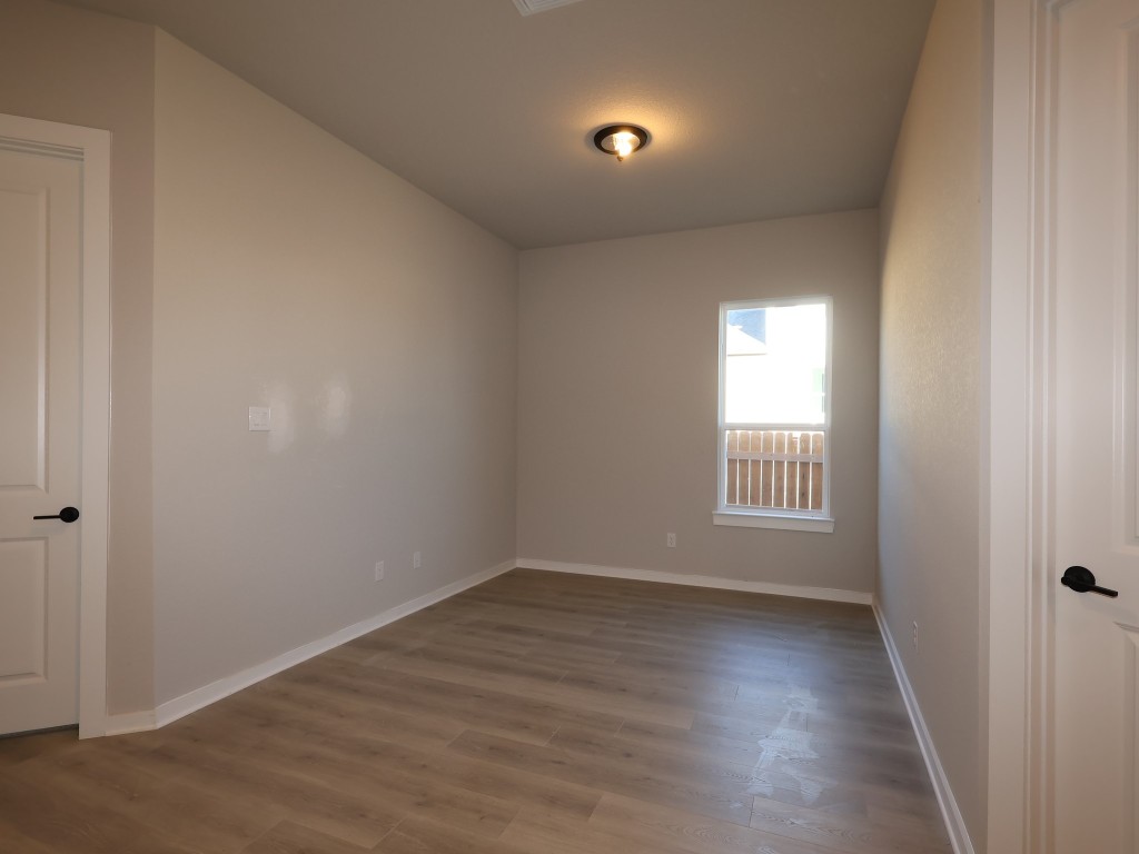 374 Bishop Wood Road Dripping Springs, TX 78620 - Photo 10 of 18 an empty room with wooden floor and windows