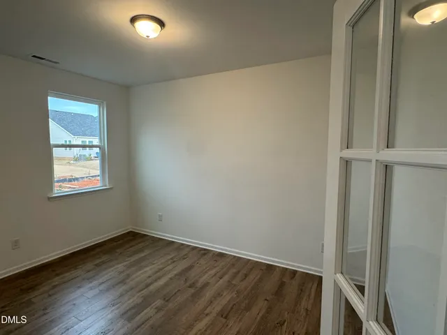 an empty room with windows and ceiling fan