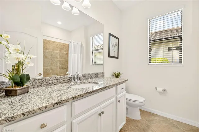 a bathroom with a granite countertop sink a toilet and a large mirror
