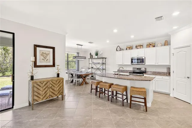 a living room with stainless steel appliances lots of furniture and a refrigerator