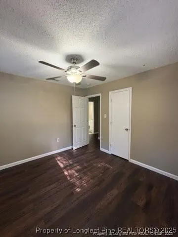 an empty room with wooden floor and fan