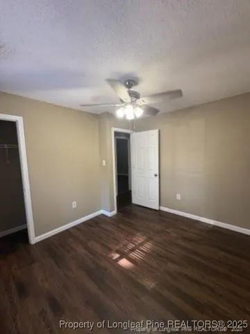 an empty room with wooden floor and fan