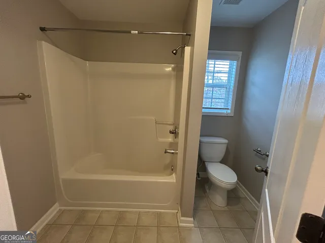 a bathroom with a granite countertop bathtub shower and toilet