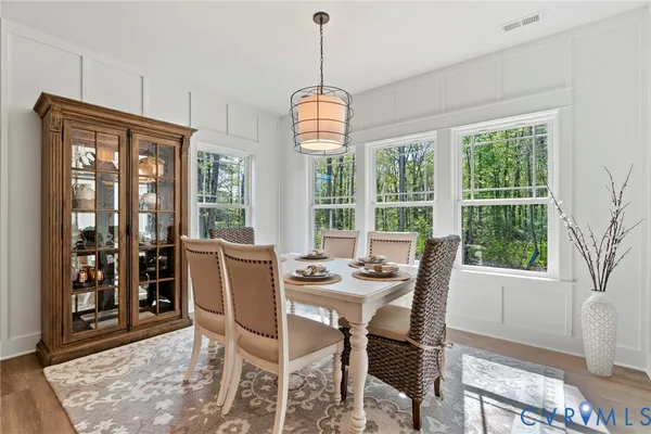 a dining room with furniture large windows a chandelier and wooden floor