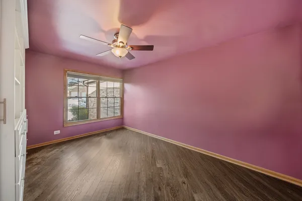 a view of an empty room with windows & wooden floor