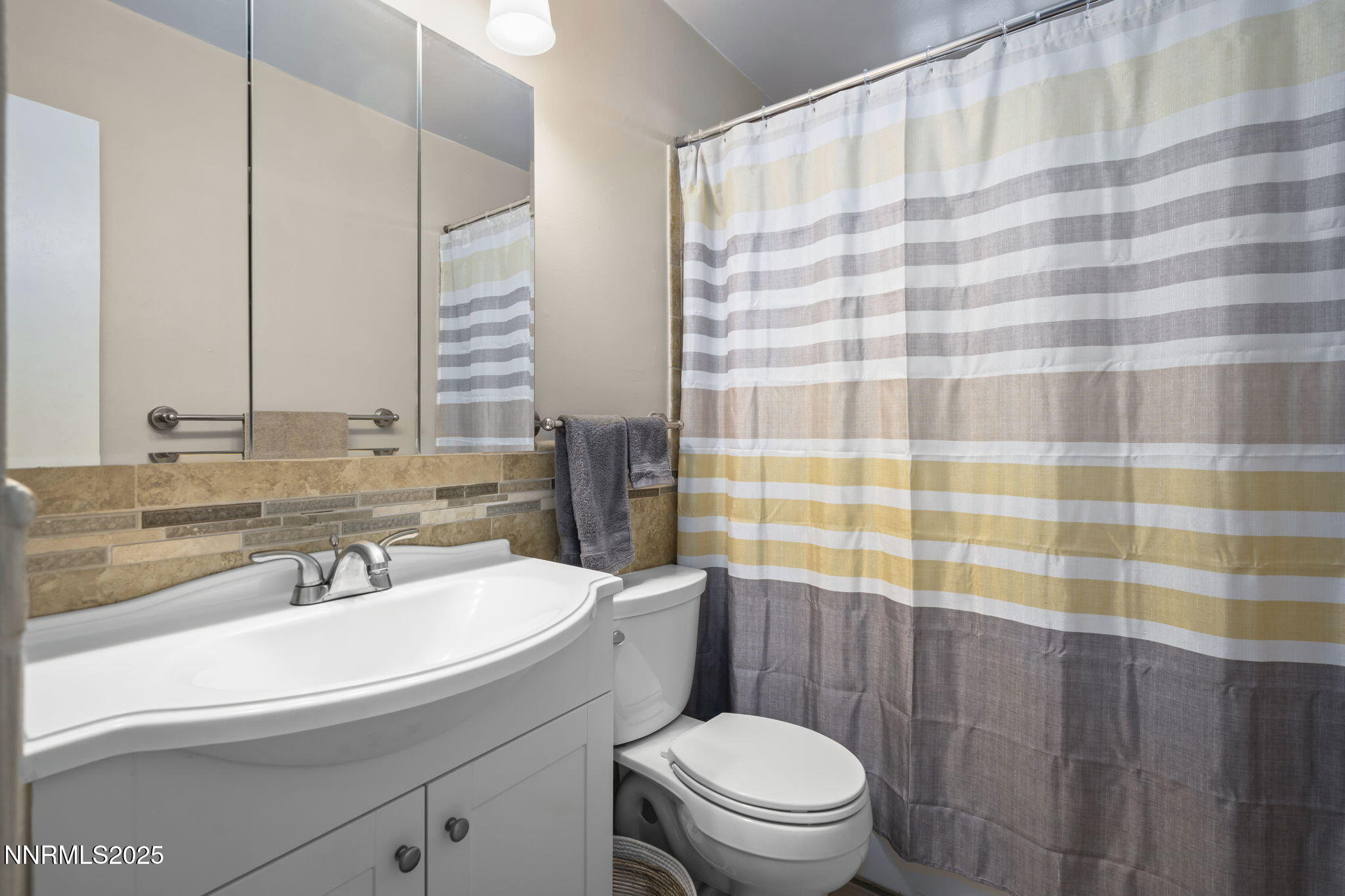 1680 Sutro Street Reno, NV 89512 - Photo 18 of 25 a bathroom with a sink a toilet a mirror and shower curtain