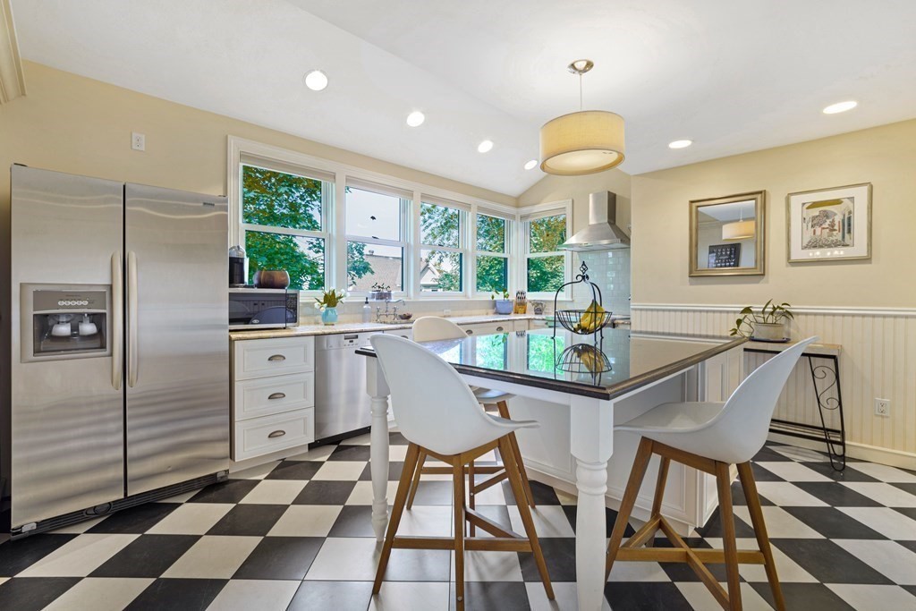 157 Winthrop Road, Unit 1 Brookline, MA 02445 - Photo 7 of 36 a kitchen with stainless steel appliances kitchen island granite countertop a refrigerator a sink a stove a dining table and chairs