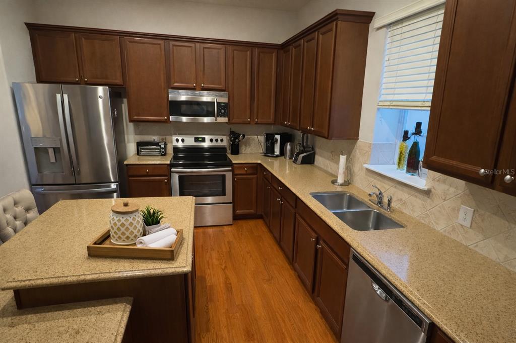 1007 Bennett Road Orlando, FL 32814 - Photo 9 of 25 a kitchen with stainless steel appliances wooden cabinets a sink and a stove