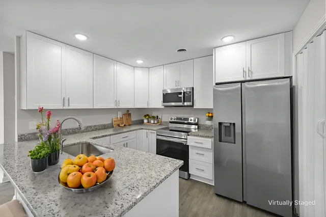 a kitchen with stainless steel appliances granite countertop a refrigerator sink stove microwave and cabinets