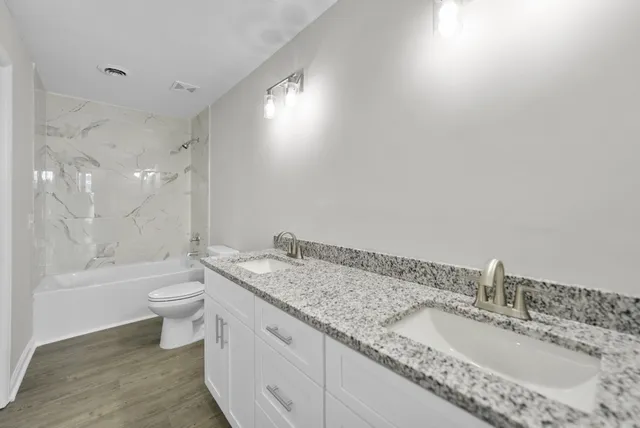 a bathroom with a granite countertop double vanity sink a mirror and a bathtub