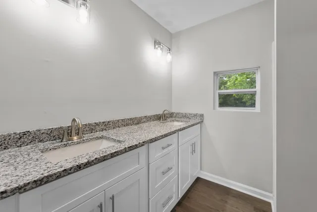 a bathroom with a granite countertop sink and white cabinets