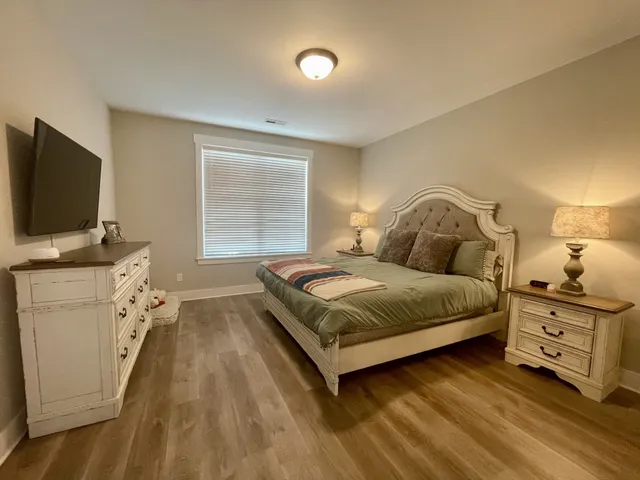 a bedroom with a bed and flat tv screen on the dresser