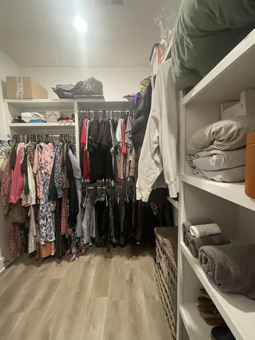 a view of walk in closet with clothes and shoes