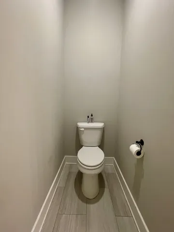 a white toilet sitting in a bathroom next to a wooden wall