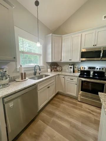 a kitchen with granite countertop a sink a window stainless steel appliances and cabinets