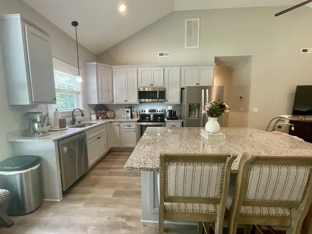 a kitchen with kitchen island granite countertop a table chairs sink and cabinets
