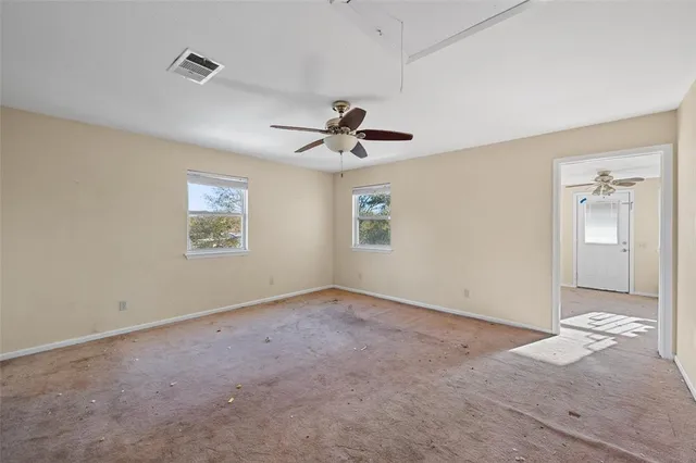 an empty room with fan and windows