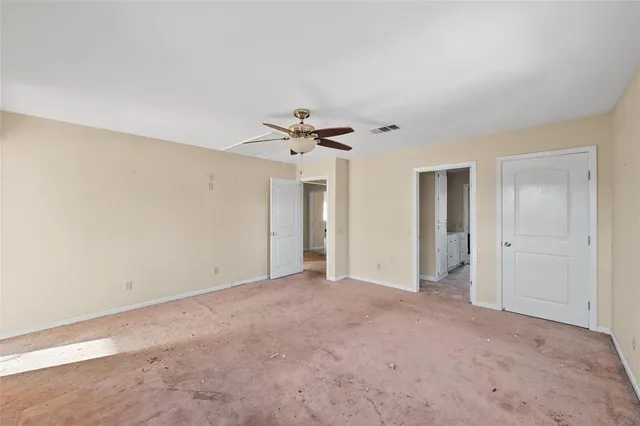a view of a big room with windows and ceiling fan