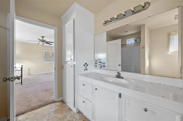 a bathroom with a granite countertop sink two mirror and a shower