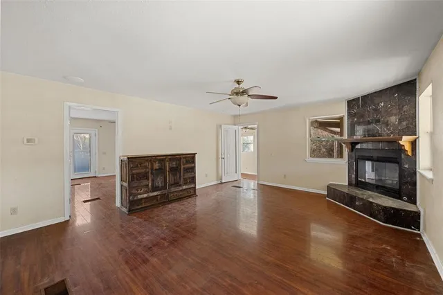 an empty room with wooden floor fireplace and windows