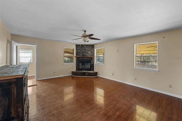 an empty room with windows and chandelier fan