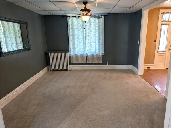 an empty room with windows and chandelier fan