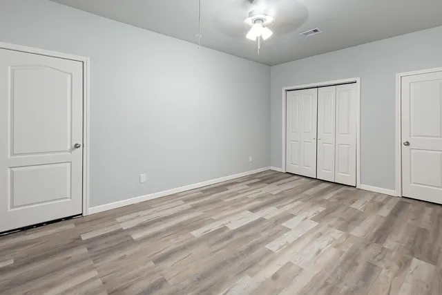 an empty room with wooden floor closet and windows