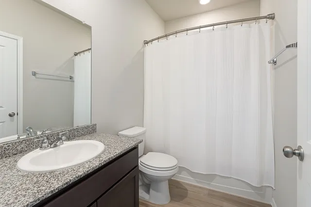 a bathroom with a granite countertop sink toilet and a mirror