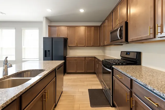 a kitchen with stainless steel appliances granite countertop a sink a stove and a refrigerator