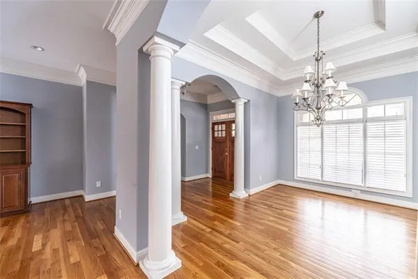a view of a room with wooden floor chandelier and a kitchen