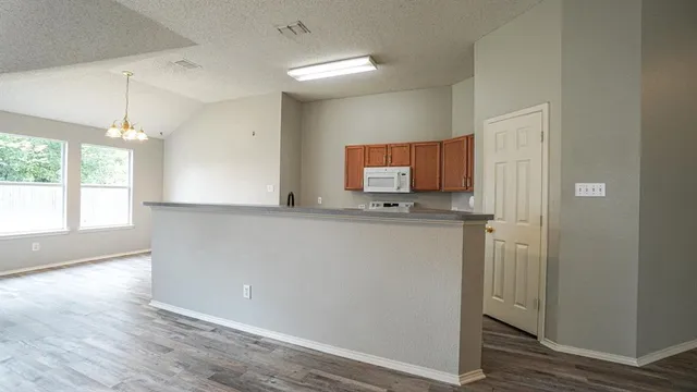 a kitchen with granite countertop cabinets stainless steel appliances and wooden floor