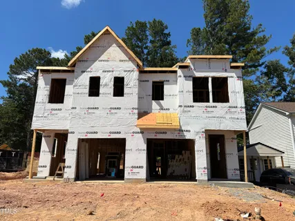 a view of a white house with wooden walls and a large tree