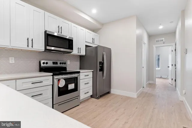 a kitchen with stainless steel appliances a refrigerator stove and white cabinets