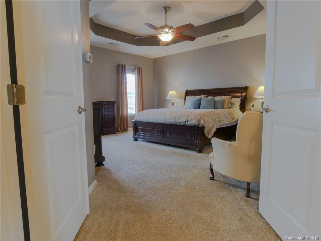 1621 Ridgehaven Road Waxhaw, NC 28173 - Photo 18 of 36 a spacious bedroom with a bed and a chandelier
