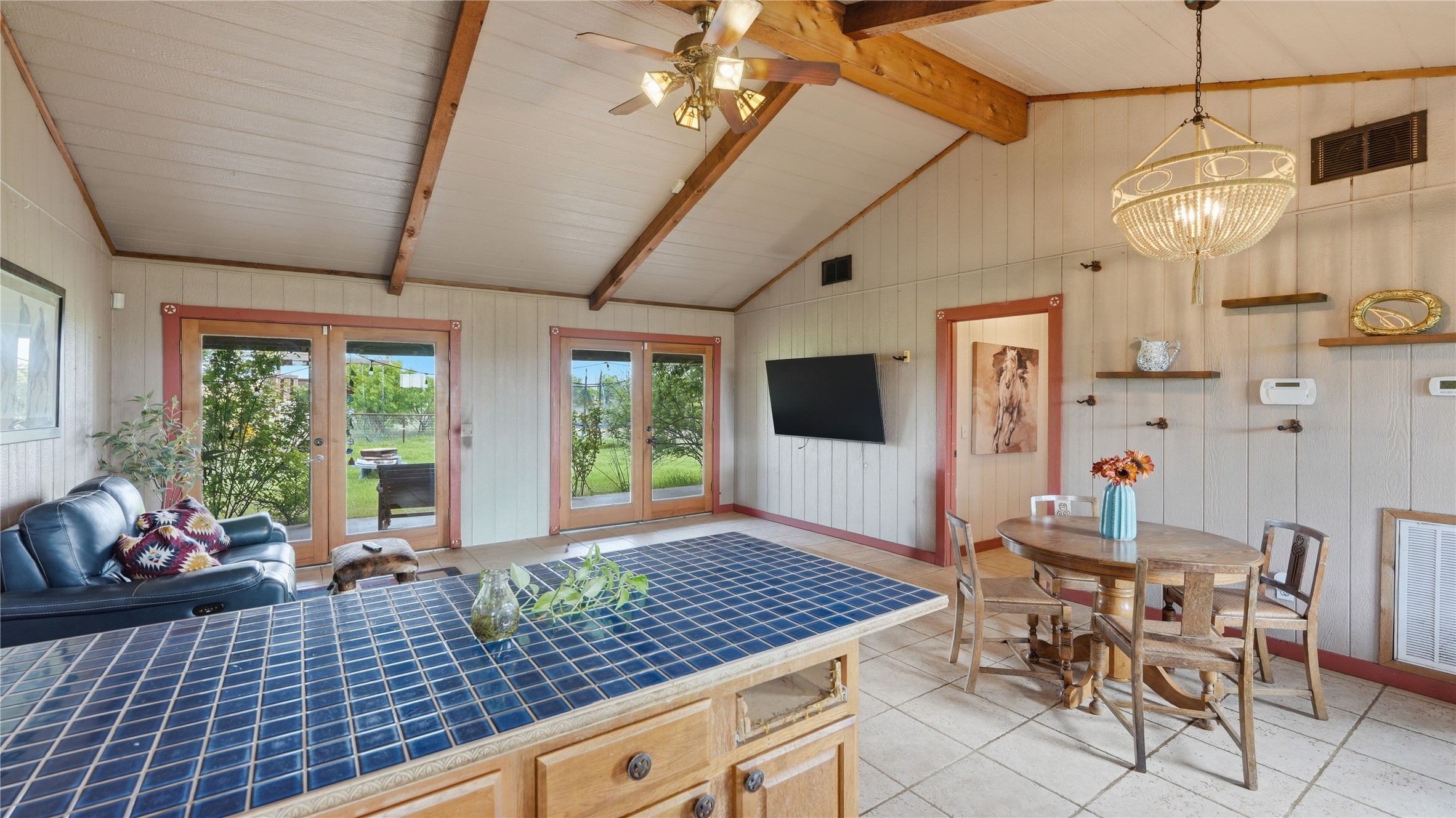 127 Offer Llano, TX 78643 - Photo 27 of 40 Kitchen island with blue tile countertop, vaulted ceiling with exposed wood beams, dual French doors, recessed wall shelving, and tile flooring