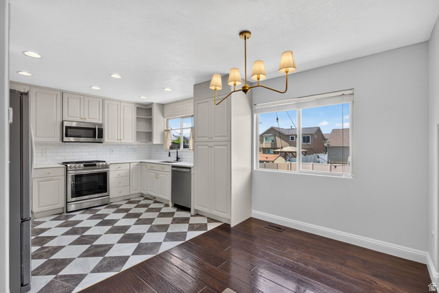 2223 North Pointe Meadow Loop Lehi, UT 84048 - Photo 12 of 56 Kitchen and dining area featuring light-toned cabinetry, stainless steel appliances, a white subway tile backsplash, and checkerboard floor tiles