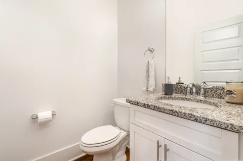 a bathroom with a granite countertop sink a toilet and a mirror
