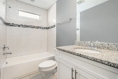 a bathroom with a granite countertop sink a toilet and shower