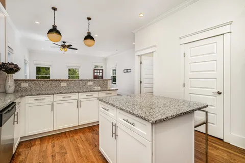 a kitchen with a sink dishwasher and white cabinets with wooden floor