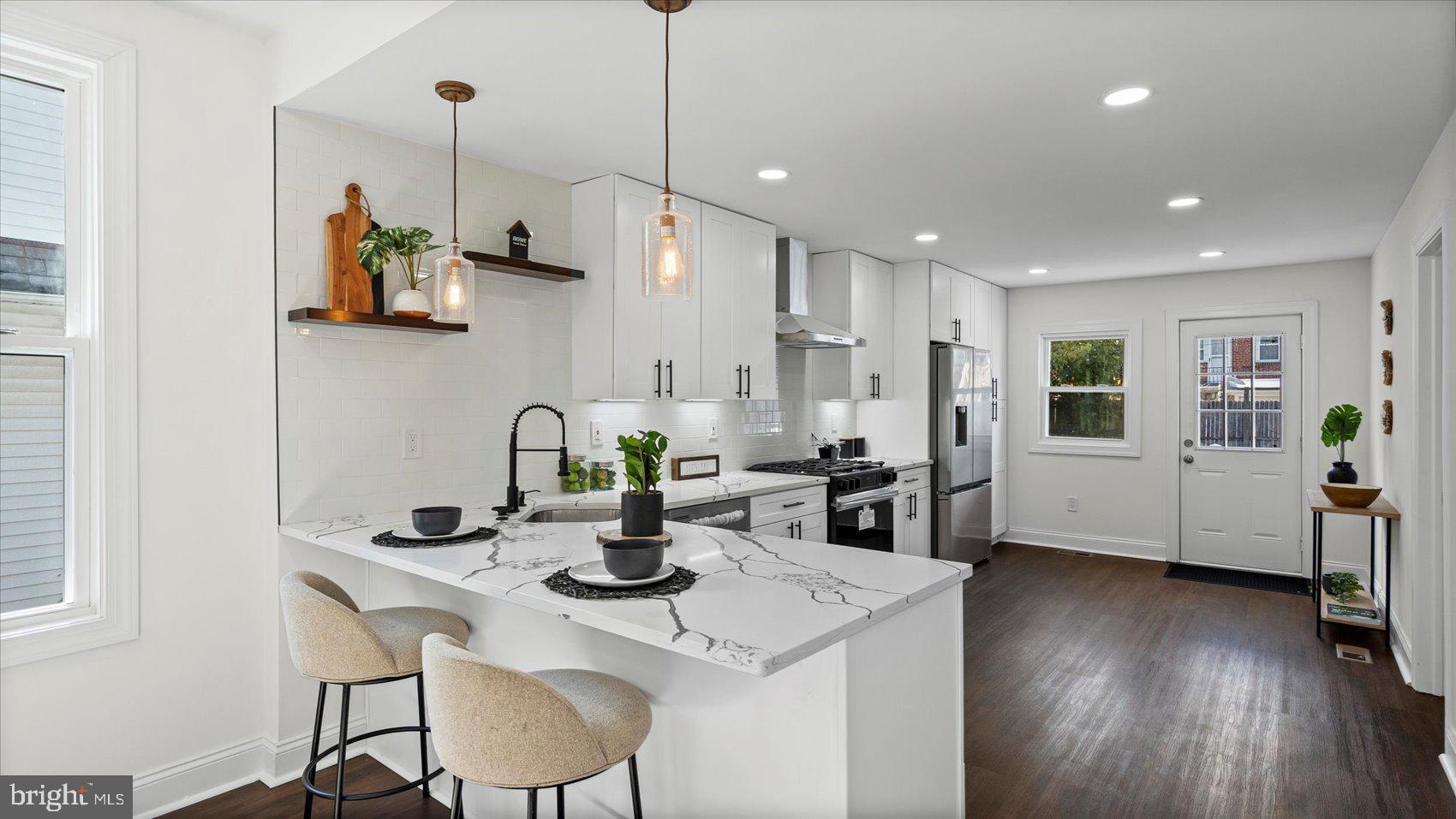 a kitchen with stainless steel appliances granite countertop a dining table chairs stove and white cabinets