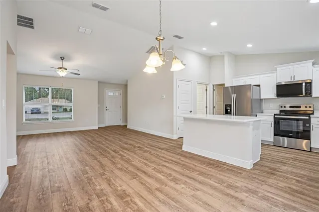 a large kitchen with stainless steel appliances lots of counter space and wooden floor