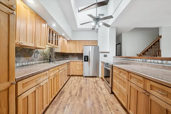 a large kitchen with stainless steel appliances granite countertop a lot of counter space and wooden floors