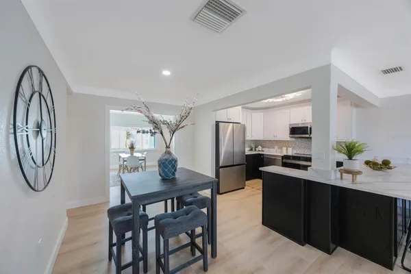 a kitchen with stainless steel appliances kitchen island granite countertop a table chairs in it and wooden floors
