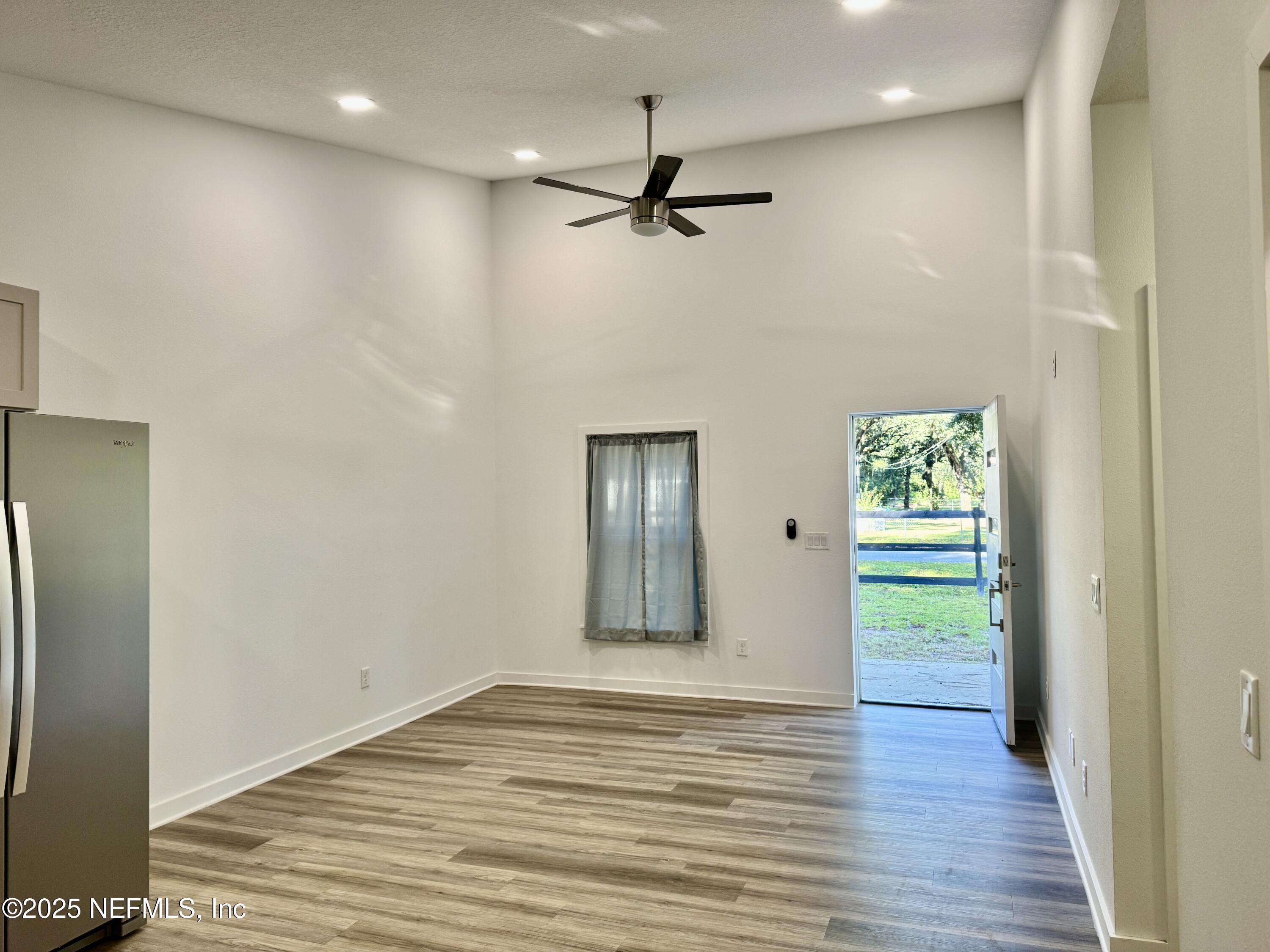 302 Azealea Avenue Interlachen, FL 32148 - Photo 17 of 38 an empty room with wooden floor a ceiling fan and windows